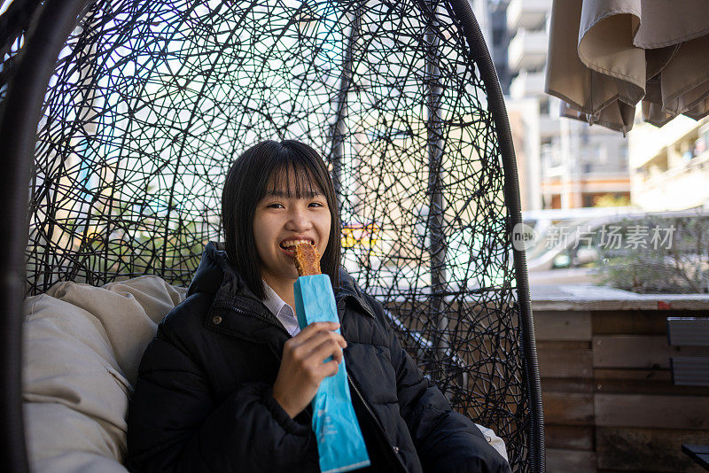 十几岁的女孩坐在椅子上吃零食