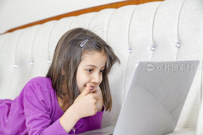 青春期前的女孩在客厅用笔记本电脑学习