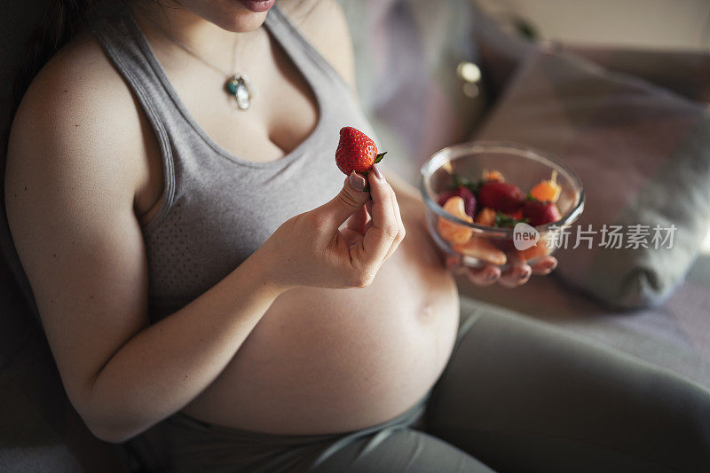 年轻孕妇在家吃水果沙拉。