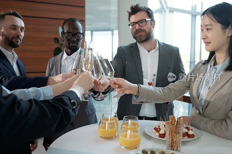 快乐的跨种族企业家在自助餐上用香槟碰杯