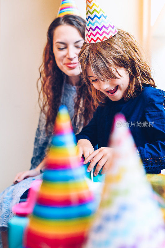 可爱快乐的小女孩和她的妈妈被五颜六色的礼物包围在生日聚会上，傻傻的，微笑着，快乐着