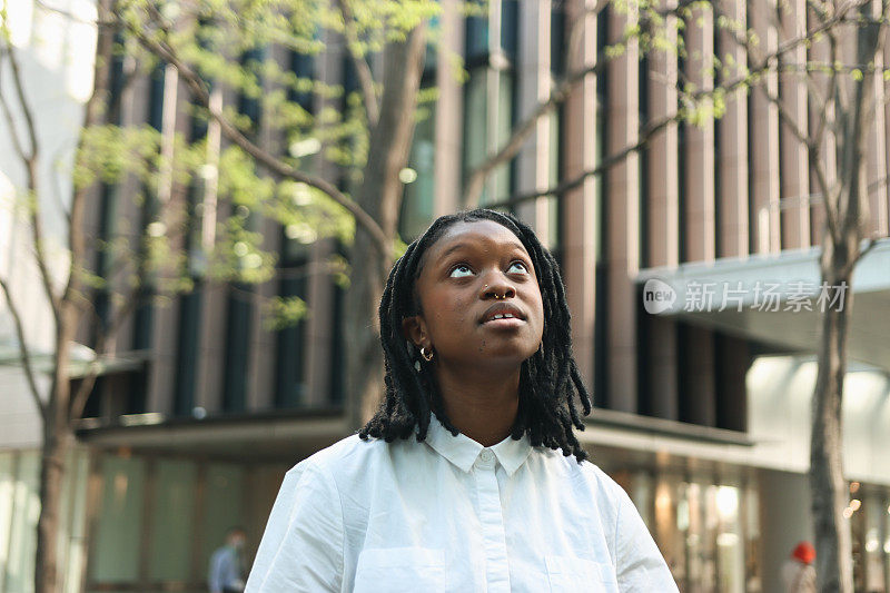 年轻的黑人妇女抬头看着前面的大楼