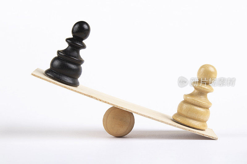棋盘上白色和黑色的棋子站在木制的跷跷板上