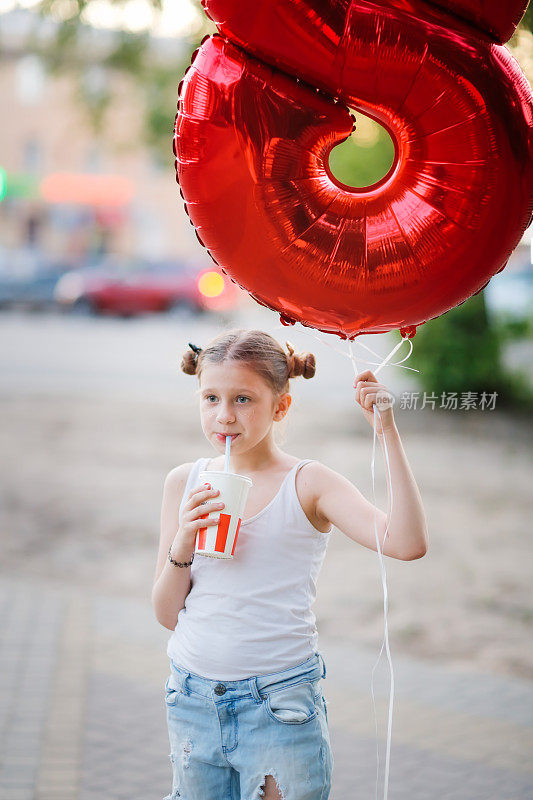 欧洲女孩用8型气球和苏打水，用吸管。孩子夏天在外面用吸管喝汽水