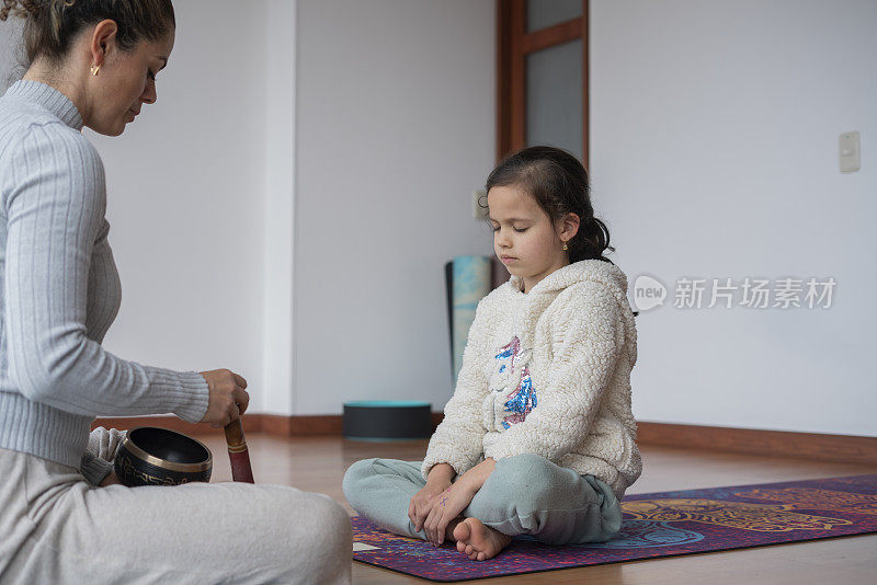 母亲和女儿在家里做瑜伽，享受一个非常私人的时刻，使他们更亲密