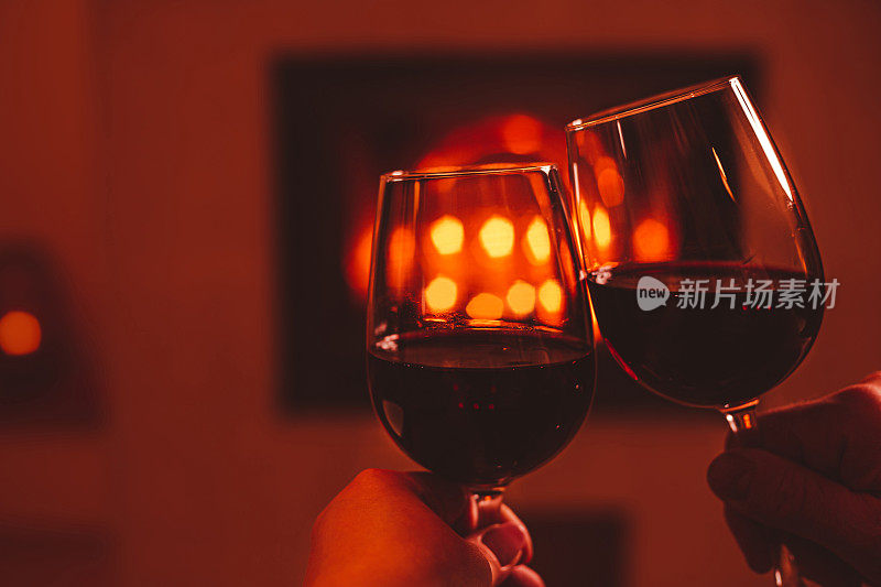 一对夫妇用红酒干杯。壁炉背景-圣诞气氛。