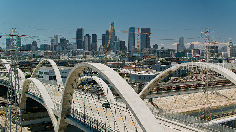 航拍的车辆驶过第六街大桥，远处是加利福尼亚州的洛杉矶市中心