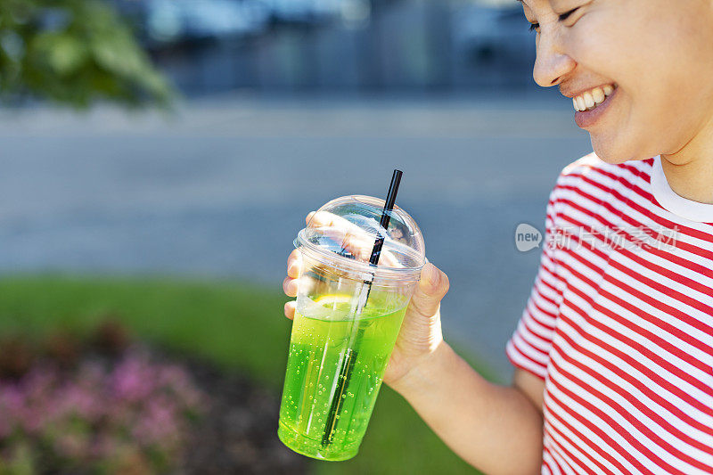 用塑料杯盛着柠檬水的女人的手