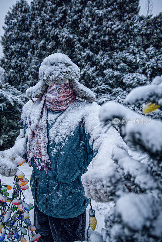 黎明时分，一名男子在摆放被雪覆盖的圣诞树彩灯时冻僵了