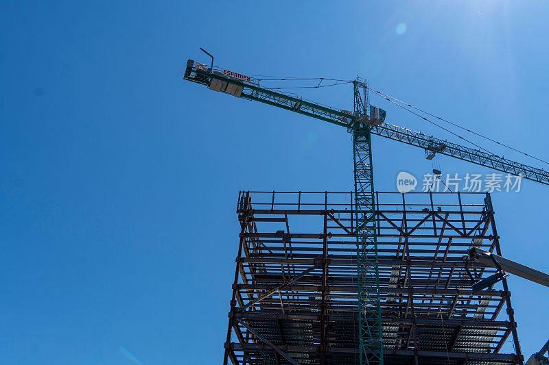 低角度拍摄的钢铁建筑结构和起重机在蓝天