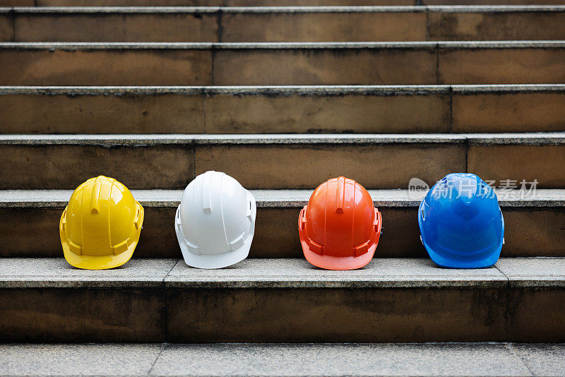 建筑工人，工程师，技术人员，在建筑工地工作的检查员的头盔。工作时戴上安全帽，防止事故发生。蓝领工人的工作设备-库存照片