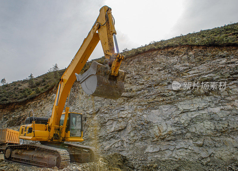 在采石场，挖掘机将岩石装载到矿用自卸卡车上。