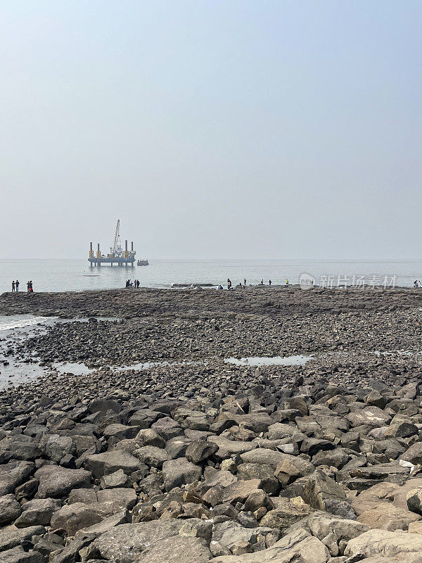 印度孟买高地，岩石海岸线，海水，低潮，印度石油天然气公司(ONGC)石油钻井平台图片