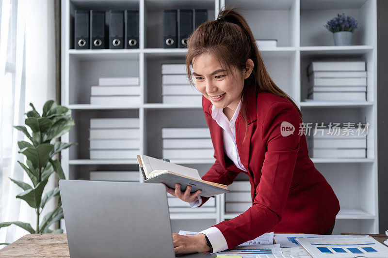 年轻的亚洲快乐的职业商务女职员坐在办公桌旁，在电脑和计算器前工作，会计师在电脑上计算税率律所账户