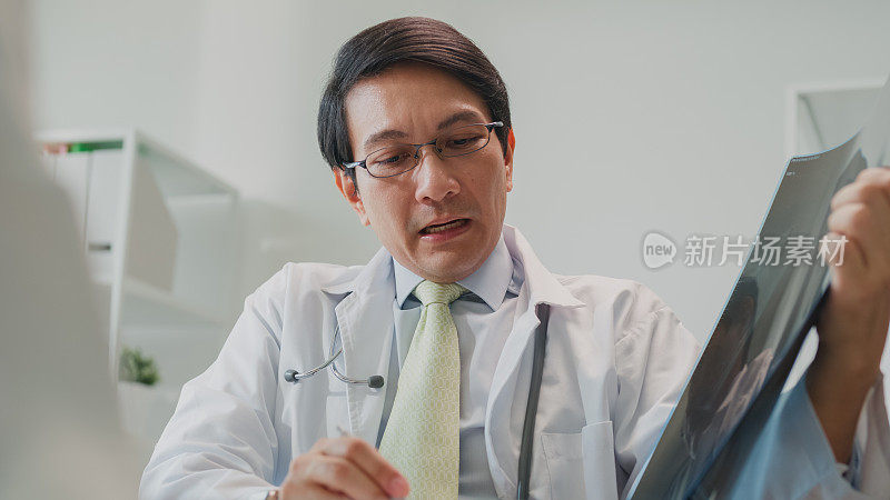图为成年亚洲男医生向住院女病人展示肺部x线检查结果的特写。医疗保健。