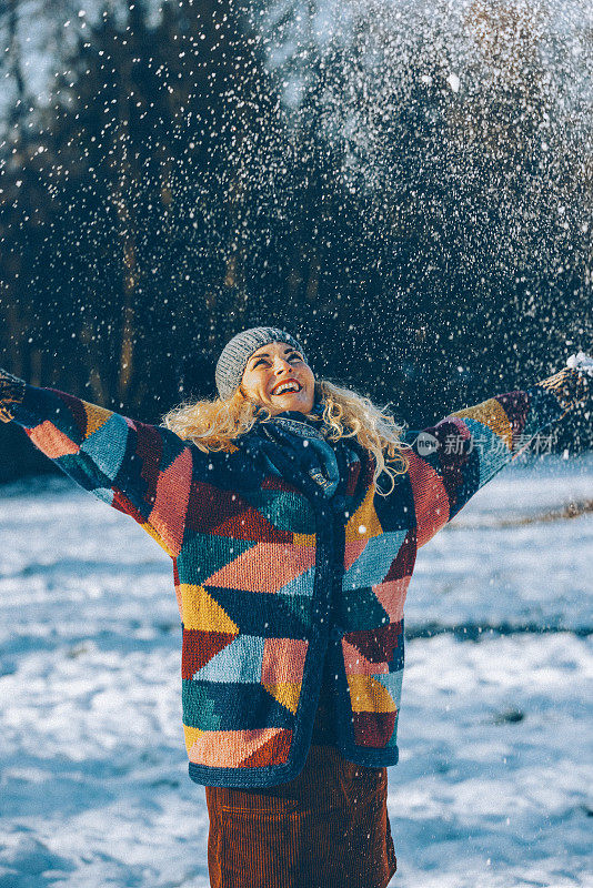 幸福的女人在冬天森林附近的白雪皑皑的草地