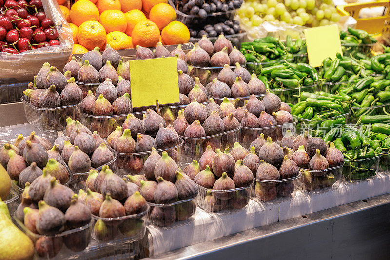 在巴塞罗那的食品市场，摊位上的紫色无花果盒子供应充足