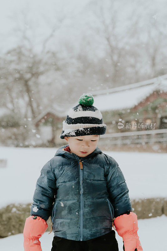 在传统的韩国房子里，男孩在下雪天玩耍