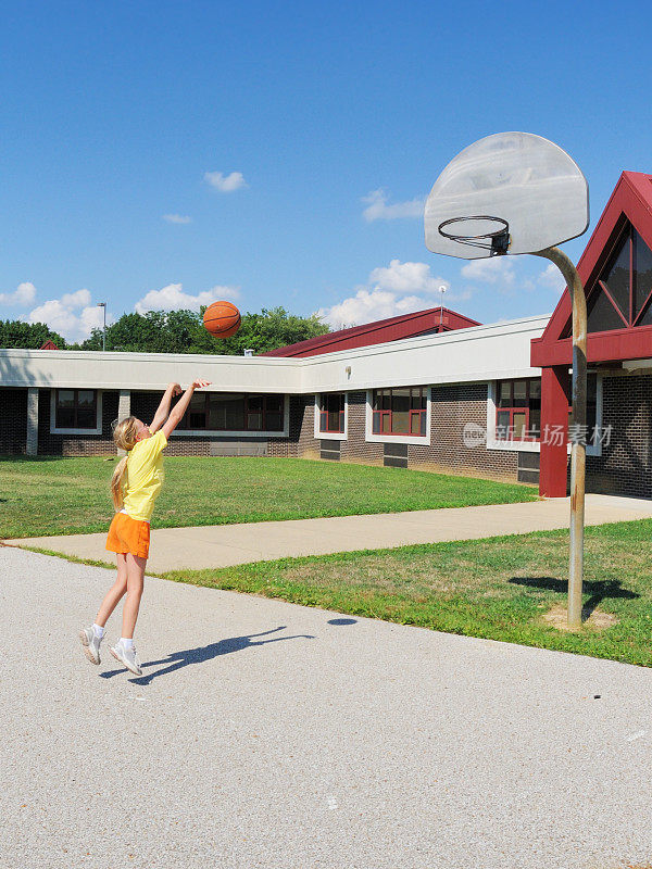 年轻的女孩女孩在学校操场上打篮球