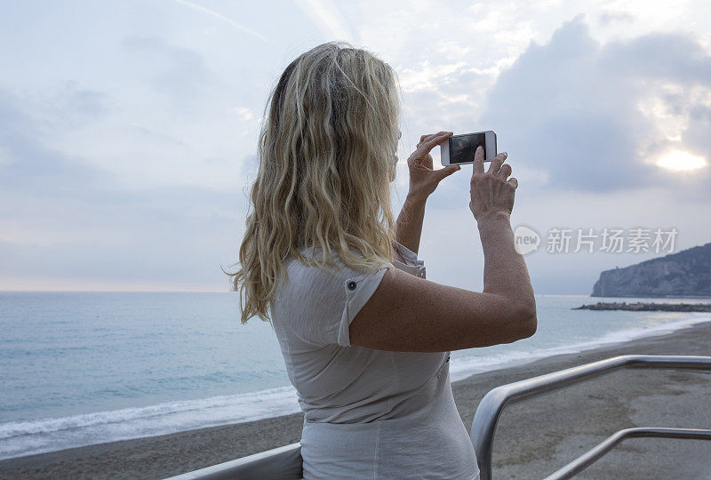 女人从海上休息的地方拍照