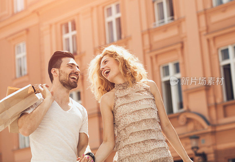一对快乐的年轻夫妇在街上购物和散步