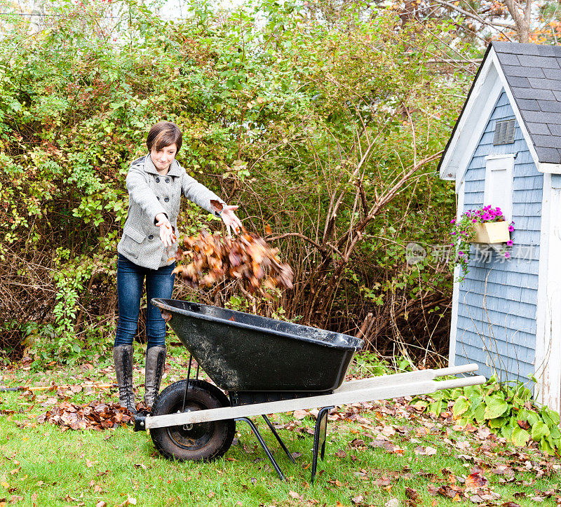 十几岁的女孩帮助清理秋天后院的树叶