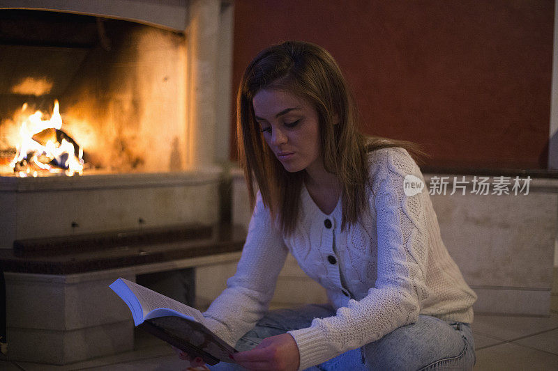 一个女人在壁炉边看书