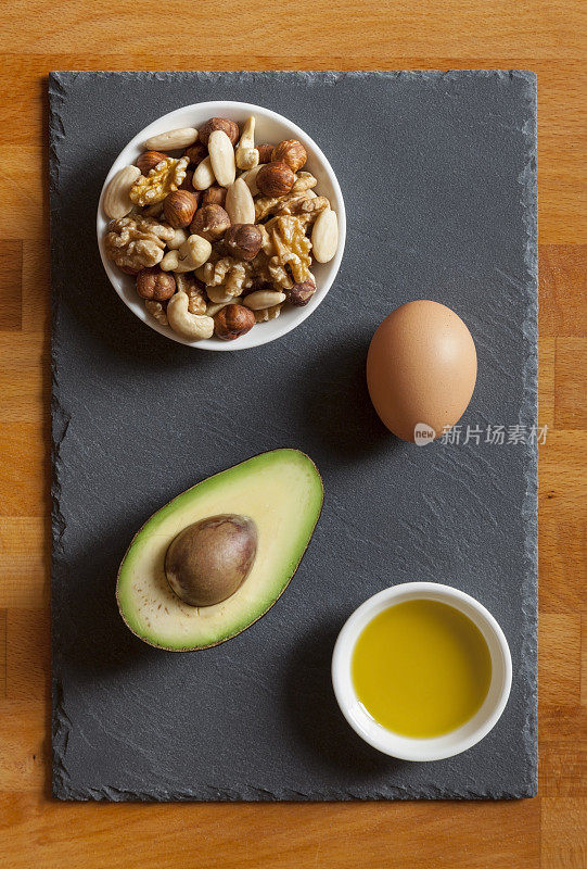 桌上放鳄梨，混合坚果，橄榄油和鸡蛋
