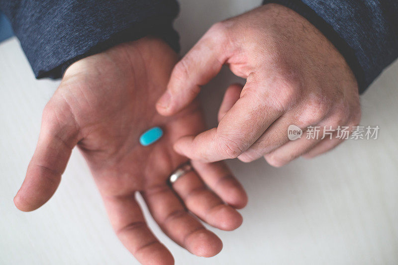 男性从近距离的手中拿着蓝色的药片