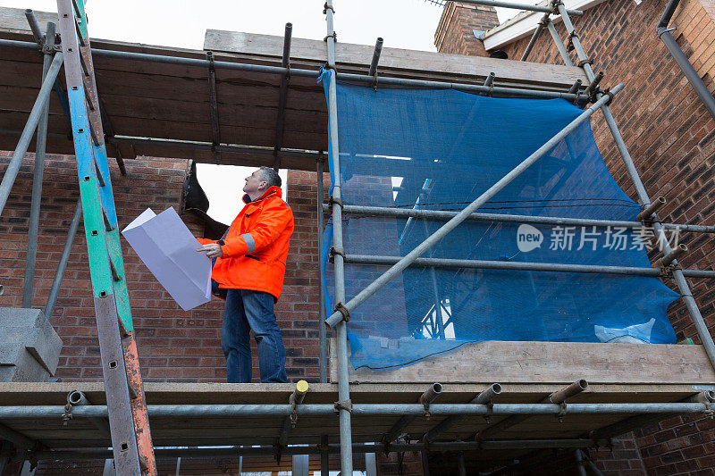 男性建筑测量师与图纸在房屋建筑工地工作