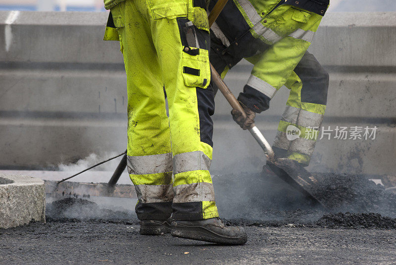 在道路建设中，工人们正在用铁锹制造沥青