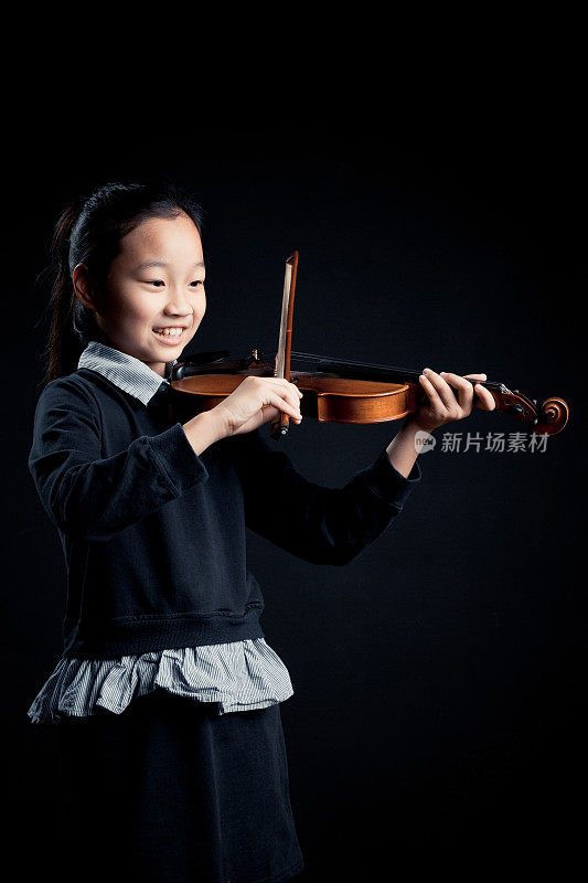 一个女孩在黑色的背景下独自拉着小提琴