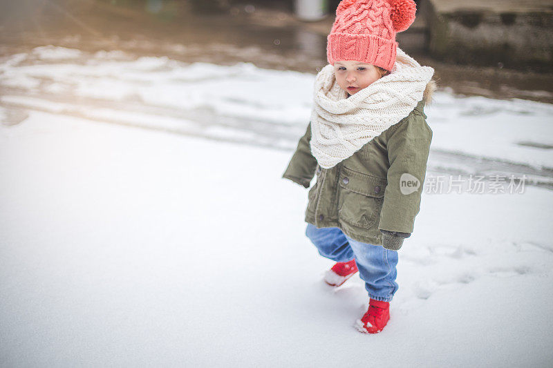 可爱的小女孩在雪地上行走