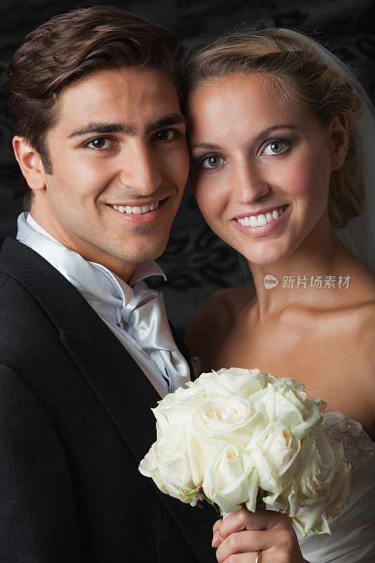 微笑优雅的年轻新婚夫妇摆姿势看着镜头