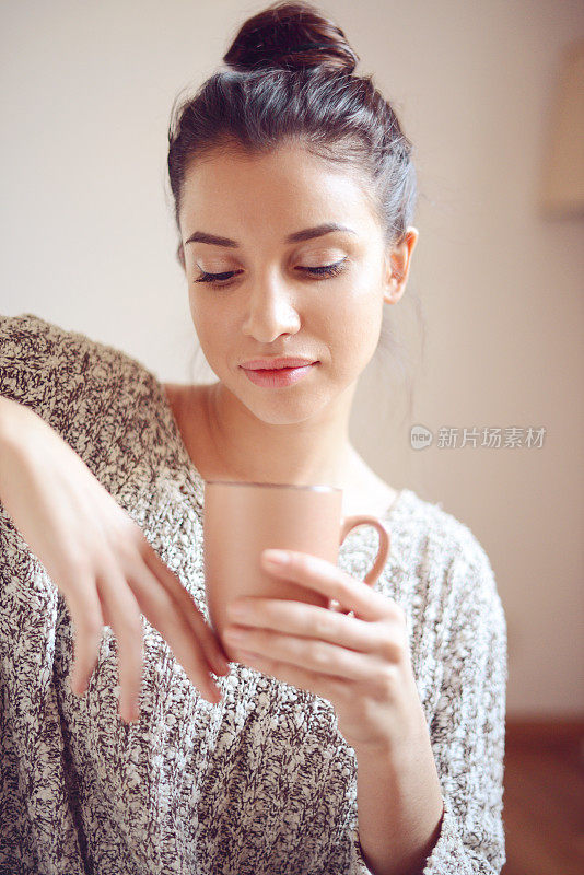 年轻女子喝着热咖啡