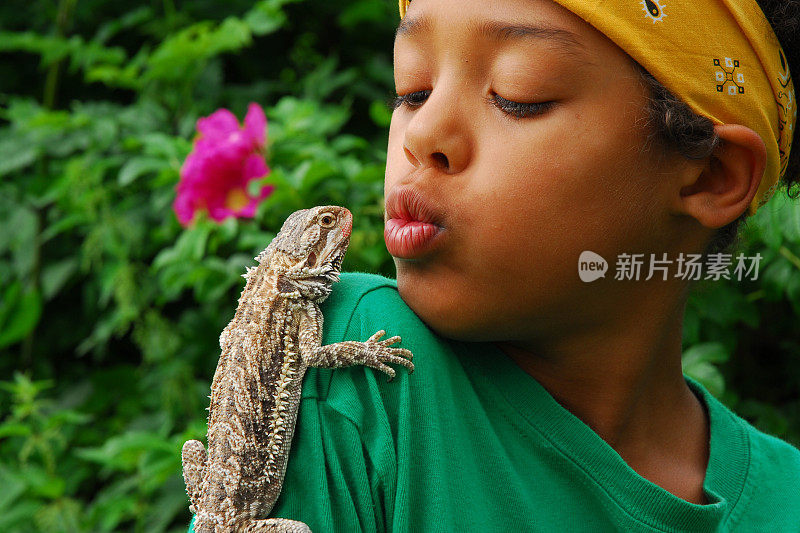 在热带花园里，蜥蜴栖息在男孩的肩膀上