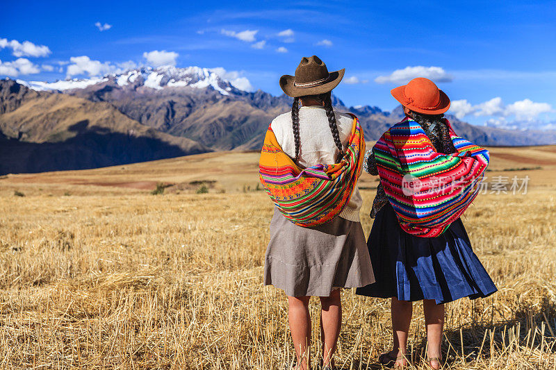 秘鲁妇女穿着民族服装穿过田野，圣谷