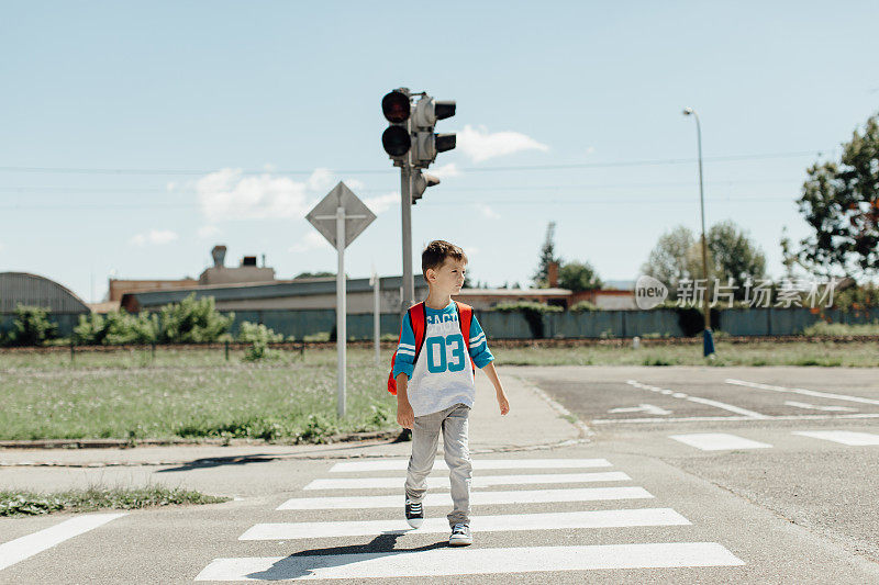 一个男孩在早晨去学校的路上过马路