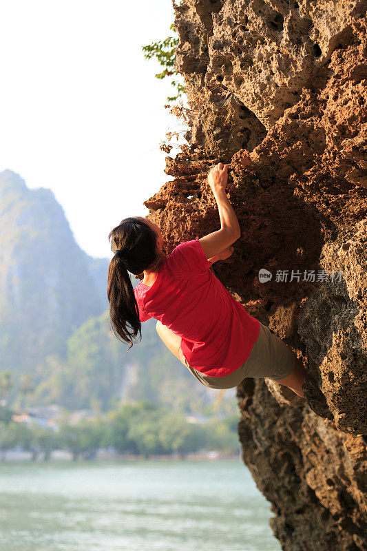 一位年轻的攀岩者正在海边的悬崖上攀岩