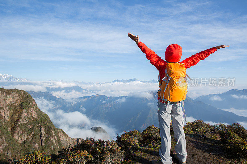 幸福成功的女性徒步旅行者站在山峰峭壁边缘
