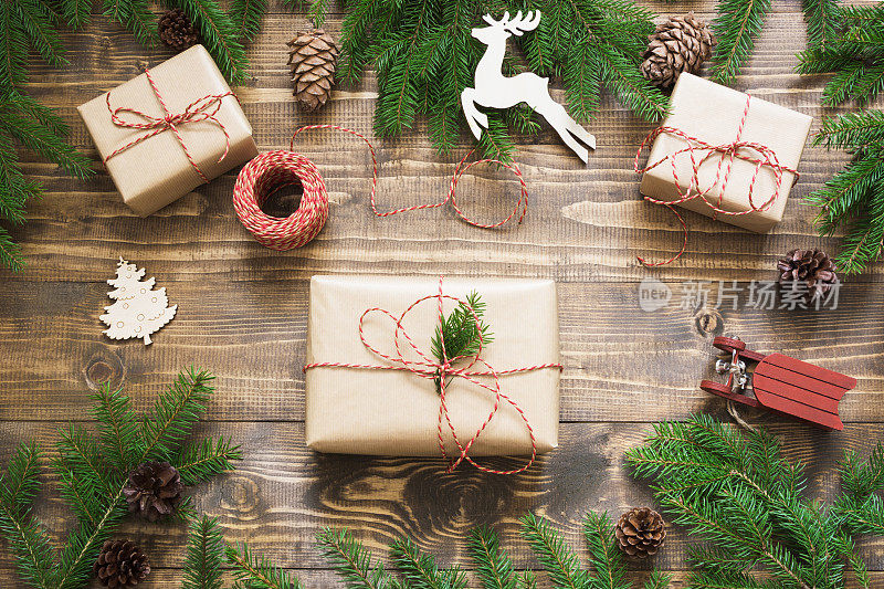 圣诞礼盒和礼物包装在牛皮纸和装饰在木板上。平的。前视图。