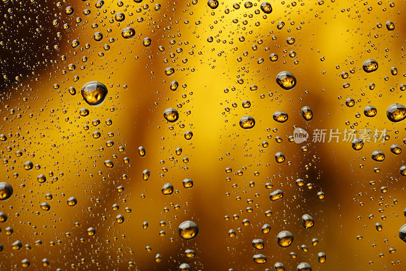 冰冷的玻璃覆盖着水滴凝结冷饮水滴金色的黄色-橙色的饮料背景雨点纹理近