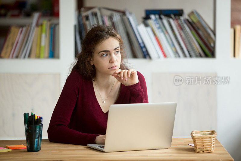 有思想的年轻女企业家坐在笔记本电脑前。