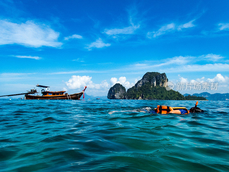 男孩浮潜在安达曼海，泰国与泰国小艇和喀斯特地层