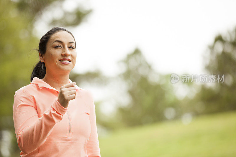 一位拉丁裔妇女在附近的公园里跑步。