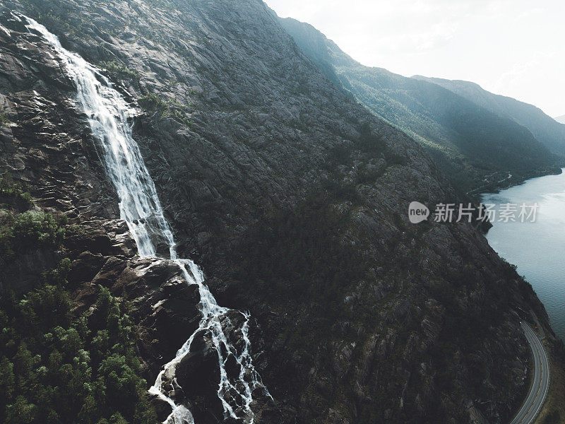 鸟瞰图，巨大的瀑布落入挪威的绿松石湖和道路