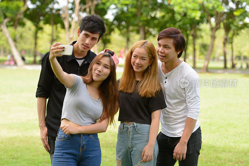 一群年轻的亚洲朋友在公园里玩的时候用手机自拍