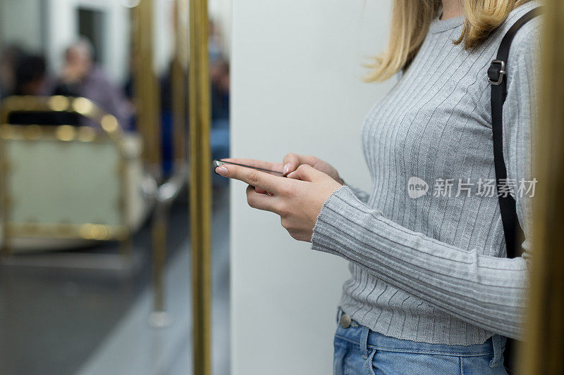 年轻女子在地铁上使用手机