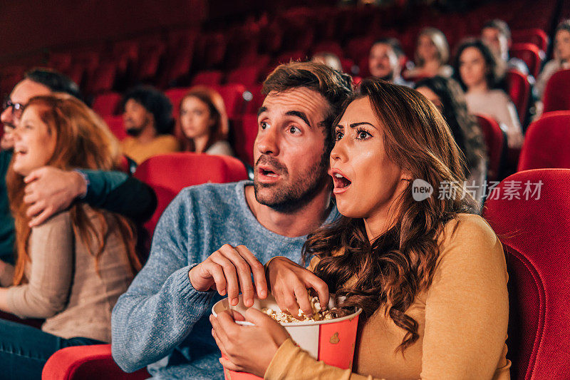 一对吓坏了的夫妇在电影院吃爆米花