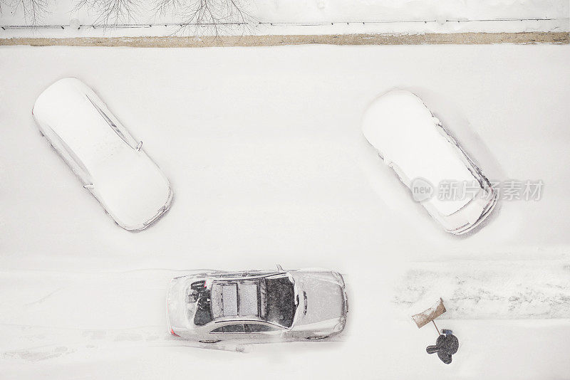 看门人在雪季清理积雪覆盖的停车位。
